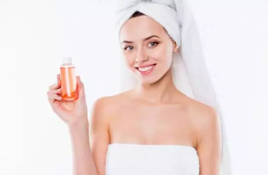 a happy young woman displaying a bottle of shimmer body lotion